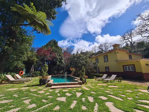 un patio trasero con piscina y una casa en Quinta da Moscadinha, en Camacha
