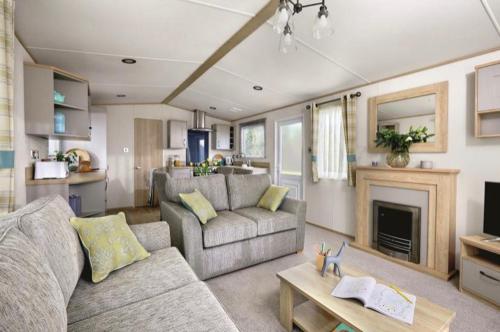 a living room with a couch and a fireplace at Hoburne Devon Bay stunning 3 bed luxury lodge in Woodland Grove in Paignton