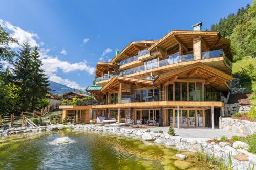 a house with a pond in front of it at Chalet Residenz Zillertal Mühlermoos in Ramsau im Zillertal