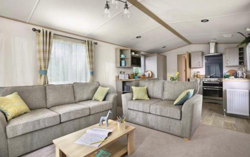 a living room with two couches and a kitchen at Hoburne Devon Bay stunning 3 bed luxury lodge in Woodland Grove in Paignton