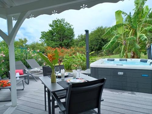 a table and chairs on a deck with a hot tub at Ti Cocon Des Iles, Bungalow de Charme Spa Privatif in Quartier du Fond Fleuri