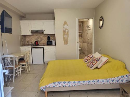 sypialnia z żółtym łóżkiem i kuchnią w obiekcie Charmant studio dans le golfe de saint tropez w mieście Le Plan-de-la-Tour