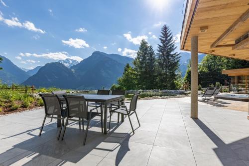 a patio with a table and chairs and mountains at Chalet Residenz Zillertal Mühlermoos in Ramsau im Zillertal