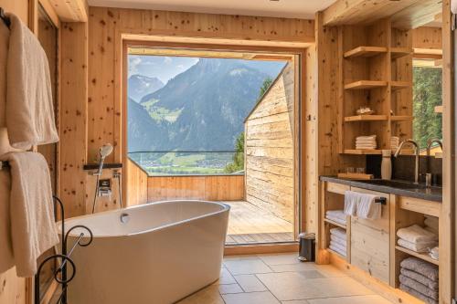 a bathroom with a tub and a large window at Chalet Residenz Zillertal Mühlermoos in Ramsau im Zillertal