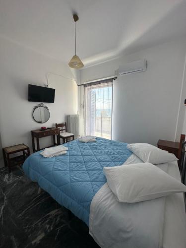 a bedroom with a large bed with a blue blanket at To Kyma in Amarinthos