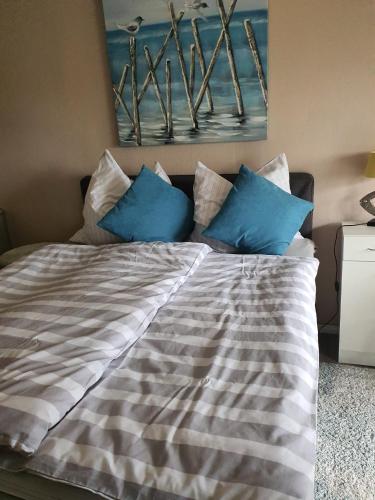 a bed with blue pillows on top of it at Bi Henning in Nordstrand