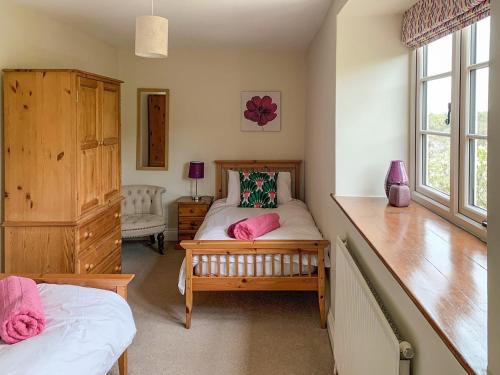 a bedroom with a bed with pink pillows on it at Hollywell Barn in Menheniot