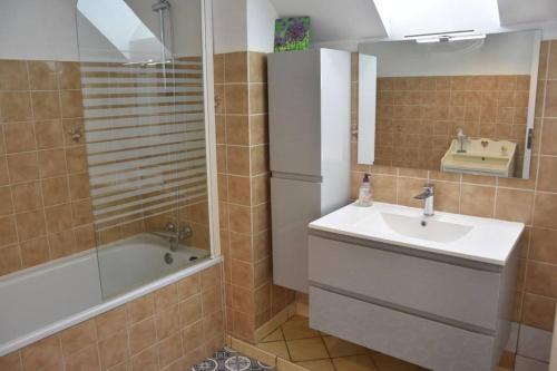 une salle de bain avec un lavabo, une baignoire et un miroir dans l'établissement Blaz an Holen - Maison avec jardin à Guimaëc, à Saint-Jean-du-Doigt