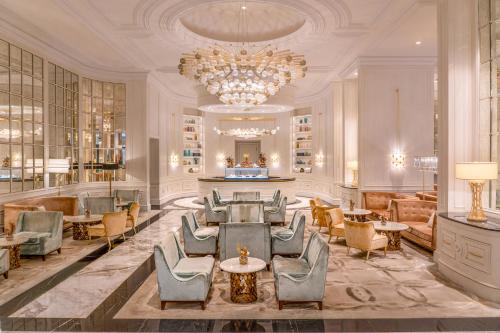 a lobby with chairs and tables and a chandelier at Fairmont Amman in Amman