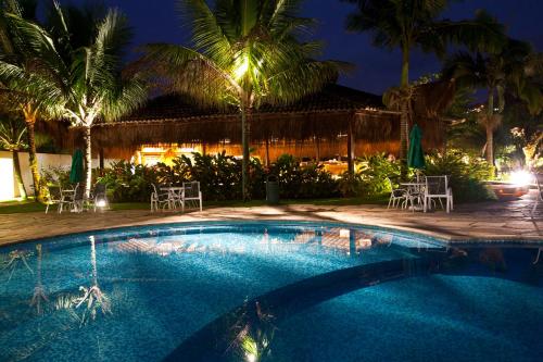 a swimming pool at night with chairs and palm trees at Hotel do Bosque ECO Resort in Angra dos Reis