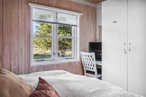 a bedroom with a bed and a window and a desk at Charmerende sommerhus - 200 m fra stranden in Marielyst