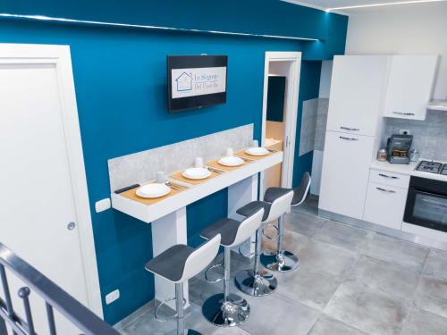 een keuken met een aanrecht met krukken en een blauwe muur bij Le Segrete del Castello, al centro Storico di Catania in Catania