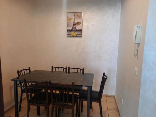 einen Esstisch mit Stühlen und ein Bild an der Wand in der Unterkunft Bel Appartement à louer in Agadir
