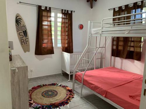 a bedroom with a bunk bed with a red bedspread at Location villa et piscine privé in Capesterre-Belle-Eau
