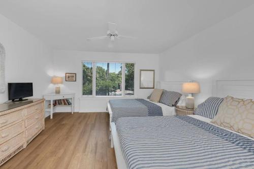 - une chambre blanche avec 2 lits et une télévision dans l'établissement Seagrove Villa 5B - Oceanside Villa in the Trees, à Isle of Palms