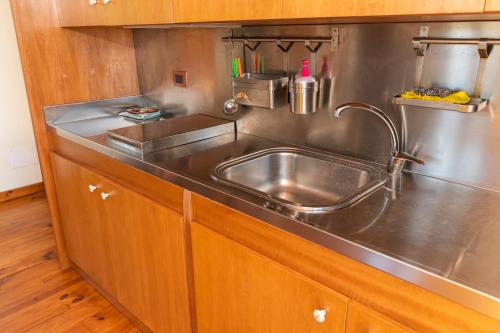 a kitchen with a stainless steel sink and wooden cabinets at Case Gemmellaro - Family&Friends in Nicolosi