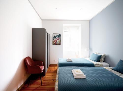 um quarto com 2 camas e uma cadeira vermelha em Lisboa Sweet Family Homestay em Lisboa