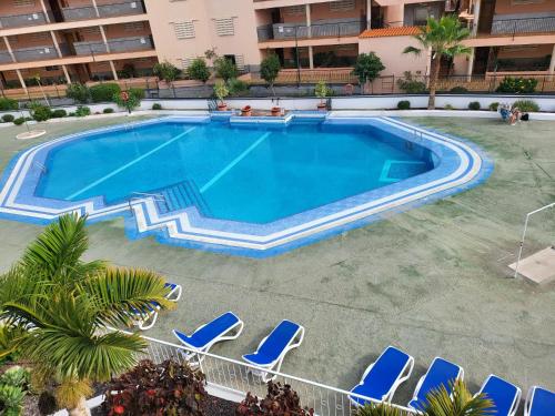een uitzicht over een zwembad met stoelen en een hotel bij Summerland Studio in Los Cristianos