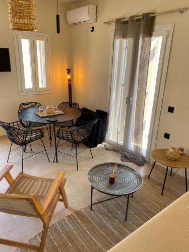 uma sala de estar com mesas, cadeiras e janelas em Thermyes Villas 3 em Kythnos