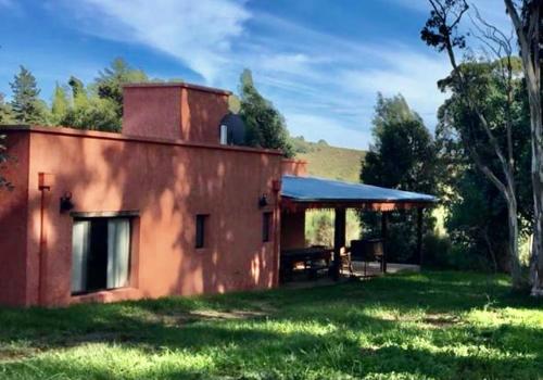 a red building with a picnic table in front of it at Quinta El Monte in Tandil