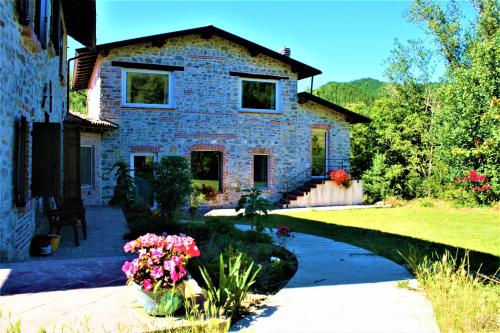 a stone house with flowers in front of it at Agriturismo Malvista in San Sebastiano Curone