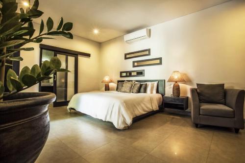 1 dormitorio con 1 cama, 1 silla y 1 planta en Villa Lamunan, en Seminyak