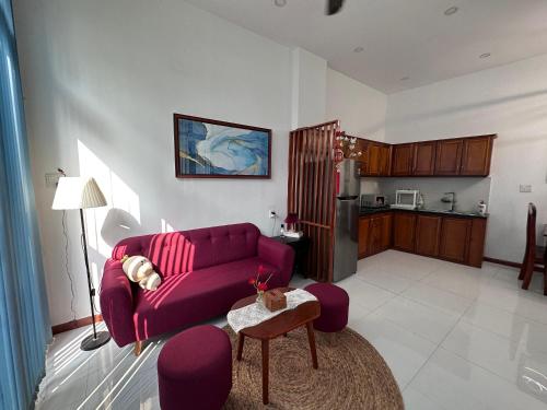 MIHA Villa & Stay في Cái Răng: غرفة معيشة مع أريكة أرجوانية ومطبخ