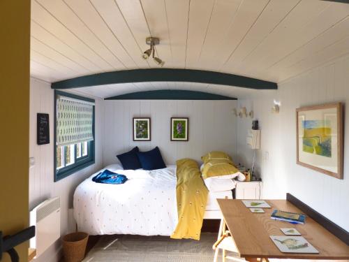 Un dormitorio con una cama y una mesa. en Oak Shepherds Hut en Wootton Fitzpaine