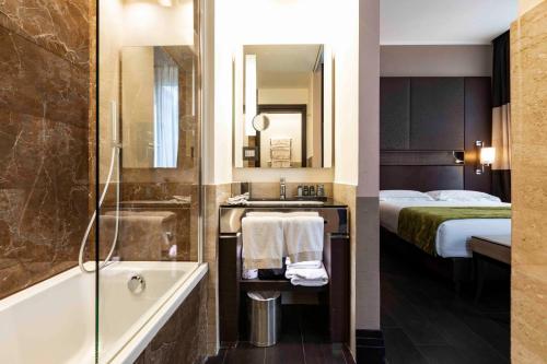 a bathroom with a tub and a sink and a bed at Rome Times Hotel in Rome