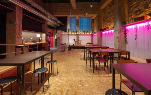 a restaurant with tables and chairs and pink lights at Ekoos Hostel, Bilbao Eko Hostel in Bilbao