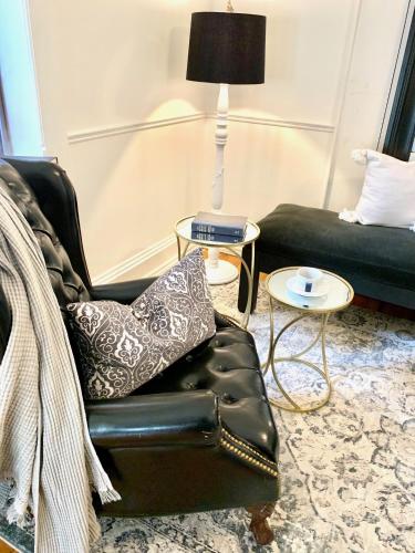 a living room with a black leather chair and a lamp at Plantation House Bed & Breakfast in Port Hope