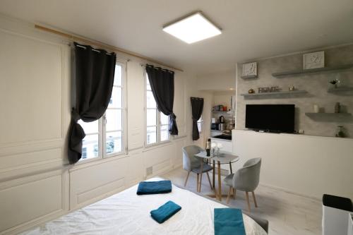 a bedroom with a bed and a table and a tv at Le Papillon de la Cathédrale - Calme - Jardin - Wifi in Troyes