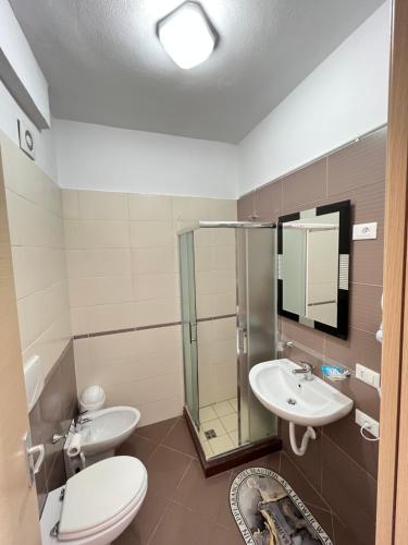 een badkamer met 2 wastafels, een toilet en een douche bij The Blue Horizon in Vlorë