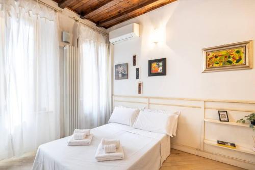 una camera da letto con un letto bianco con due asciugamani di [TICINESE-DUOMO ELEGANTE] Centrale con A/C a Milano