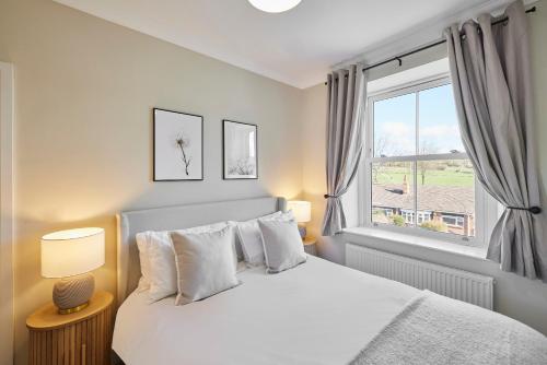 a bedroom with a white bed and a window at Host & Stay - Oakwell Cottage in Birstall