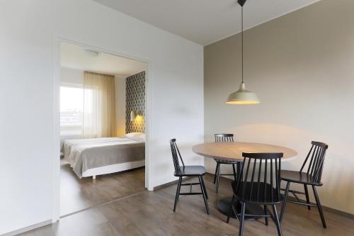 ヘルシンキにあるフォーノム サービス アパートメンツ ヘルシンキ ラピンラーデンカトゥのテーブル、椅子、ベッドが備わる客室です。