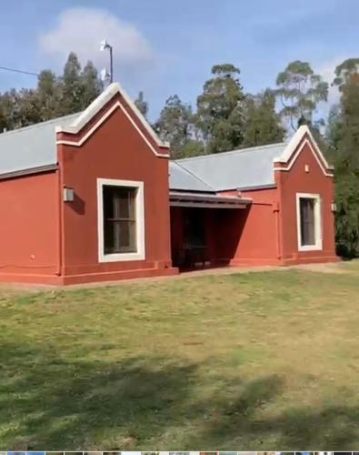 a red building with a grass field in front of it at Quinta El Monte in Tandil