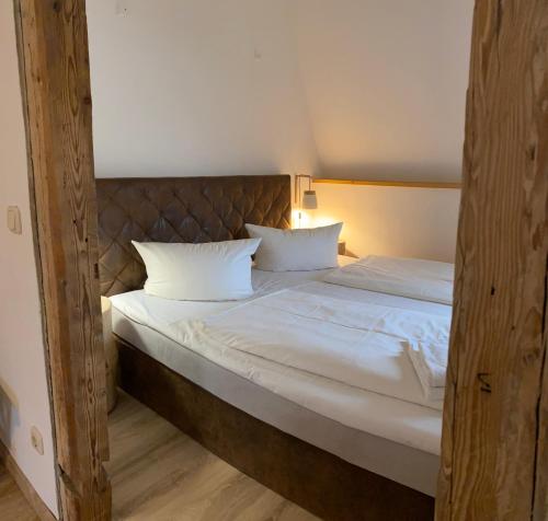 a bed with white sheets and pillows in a room at Fasa Lodge in Kurort Oberwiesenthal