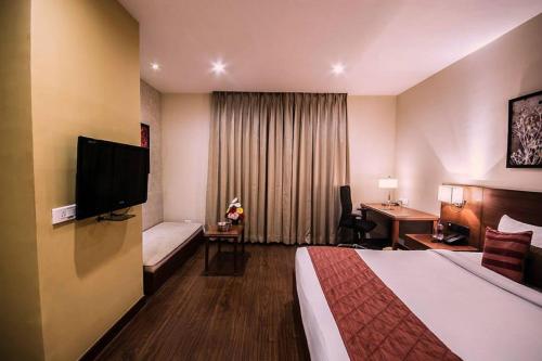 Cette chambre comprend un lit et une télévision à écran plat. dans l'établissement The Altruist Business Hotel Hitech, à Hyderabad