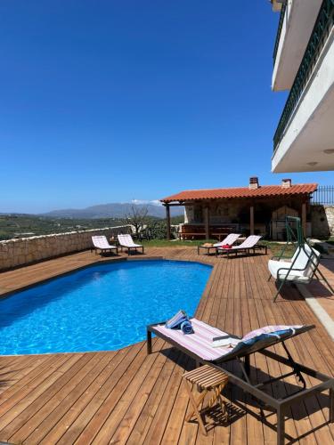 una piscina en una terraza de madera con sillas y una casa en Olive Villa, en Xirokámbion