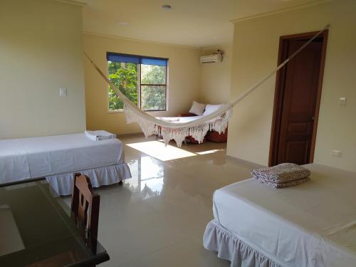 a room with two beds and a hammock in it at Posada Hato el Diamante in San Luis de Palenque