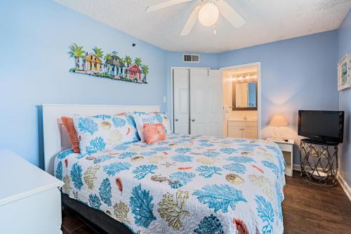 a bedroom with a bed with blue walls and a tv at Tradewinds #1008 in Orange Beach