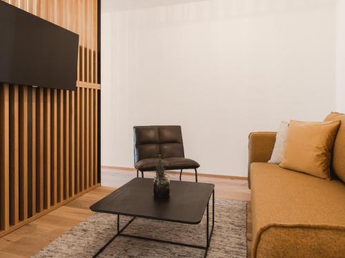 a living room with a couch and a chair at alpina&more APARTMENTS I ZIMMER in Serfaus