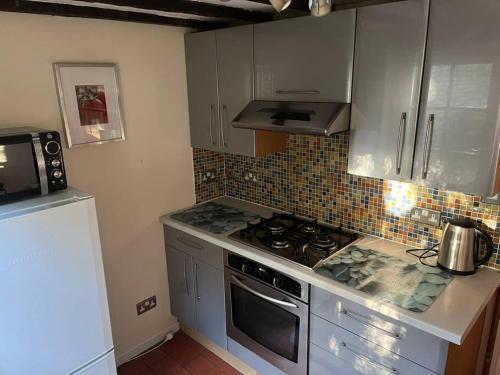 a kitchen with a stove and a microwave at Historic Town Centre Cottage in Bury Saint Edmunds