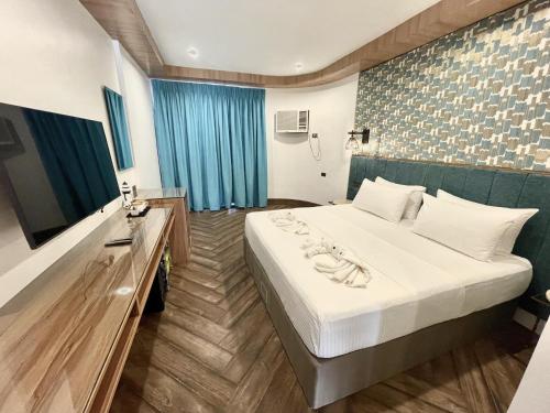 um quarto de hotel com uma cama e uma televisão em Lighthouse Point Hotel em Dumaguete