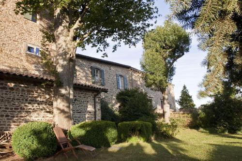 ein Gebäude mit einem Baum und einer Bank in einem Hof in der Unterkunft Chateau De Riverie chambres et table d'hôtes in Riverie