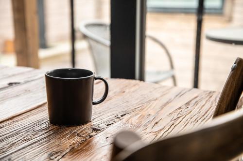 a black coffee cup sitting on a wooden table at Laxhall Hotell Krog Konferens in Torsö