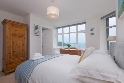 a bedroom with a large white bed and windows at 4 Pentowan Court in St Ives
