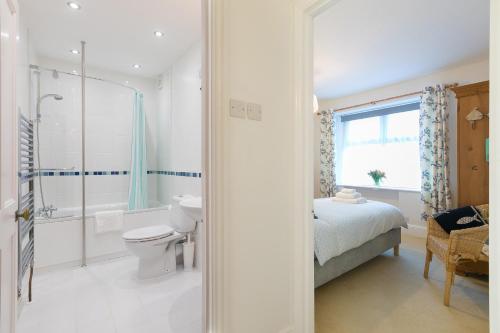 a bathroom with a toilet and a shower and a bed at 4 Pentowan Court in St Ives