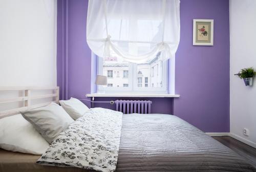 1 dormitorio con paredes moradas y 1 cama con ventana en Apartament Zgoda, en Gdynia